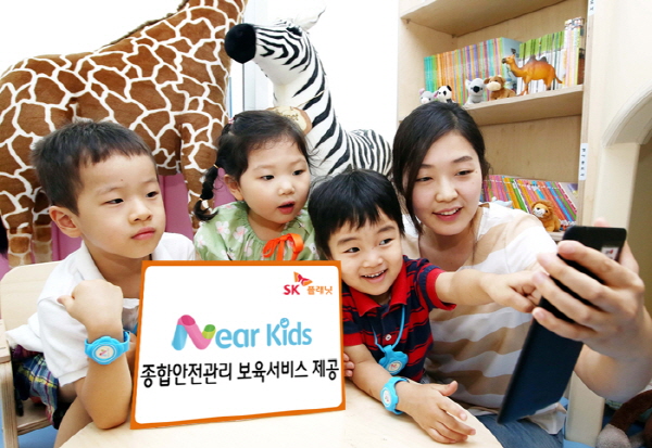 SK플래닛 니어키즈(Near Kids),보육시설 종합 안전 관리 서비스 제공 관련 홍보사진입니다. 왼쪽 배너에는 니어키즈 종합관리 보육 서비스 제공이라고 적힌 배너가 있고 오른쪽 모델은 핸드폰을 들고 아이들과 함께 있습니다.